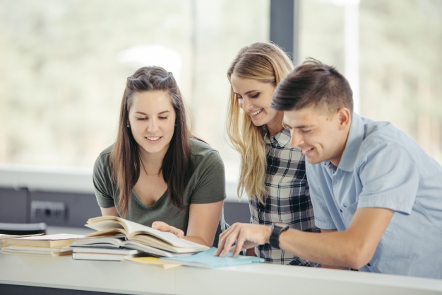 happy-classmates-at-table-in-library_23-2147678931
