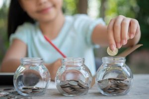 Cute asian little girl playing with coins making stacks of money
